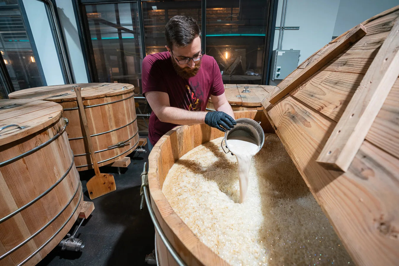 A Chuckanut Bay Distillery team member pitching yeast into a traditional wooden washback