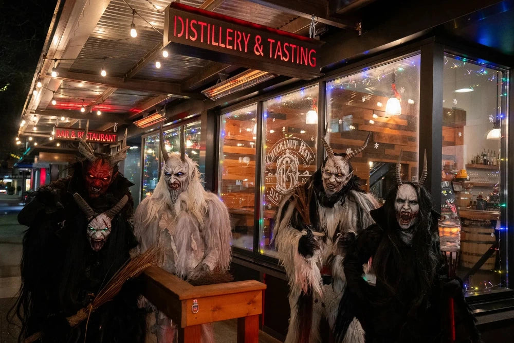 Four people in elaborate costumes standing in front of a distillery entrance with 'Distillery & Tasting' sign.